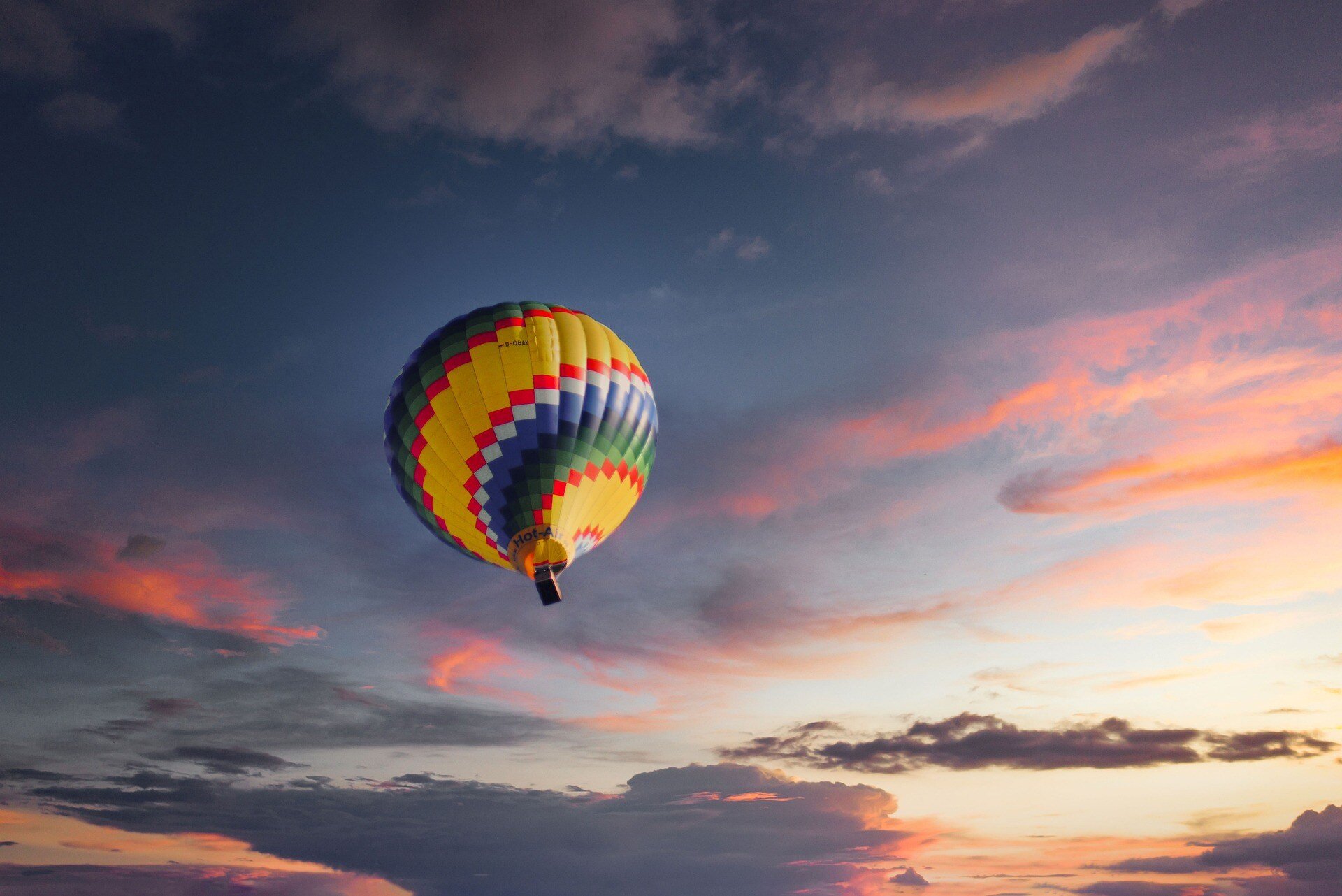 colorful hot air balloon floating in front of the sunset sky